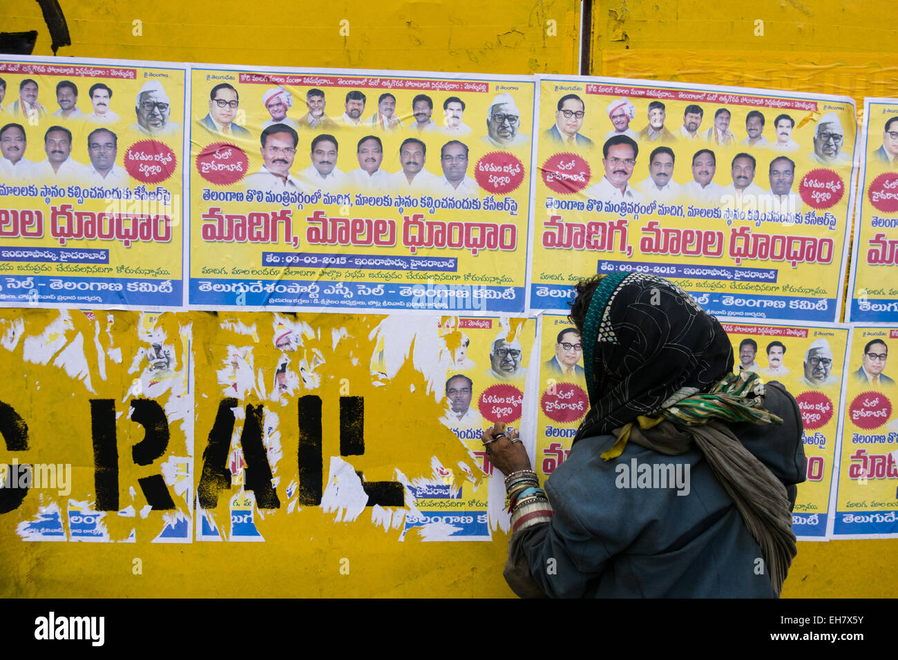 indische Frau entfernt Poster an die Wand geklebt Stockfoto