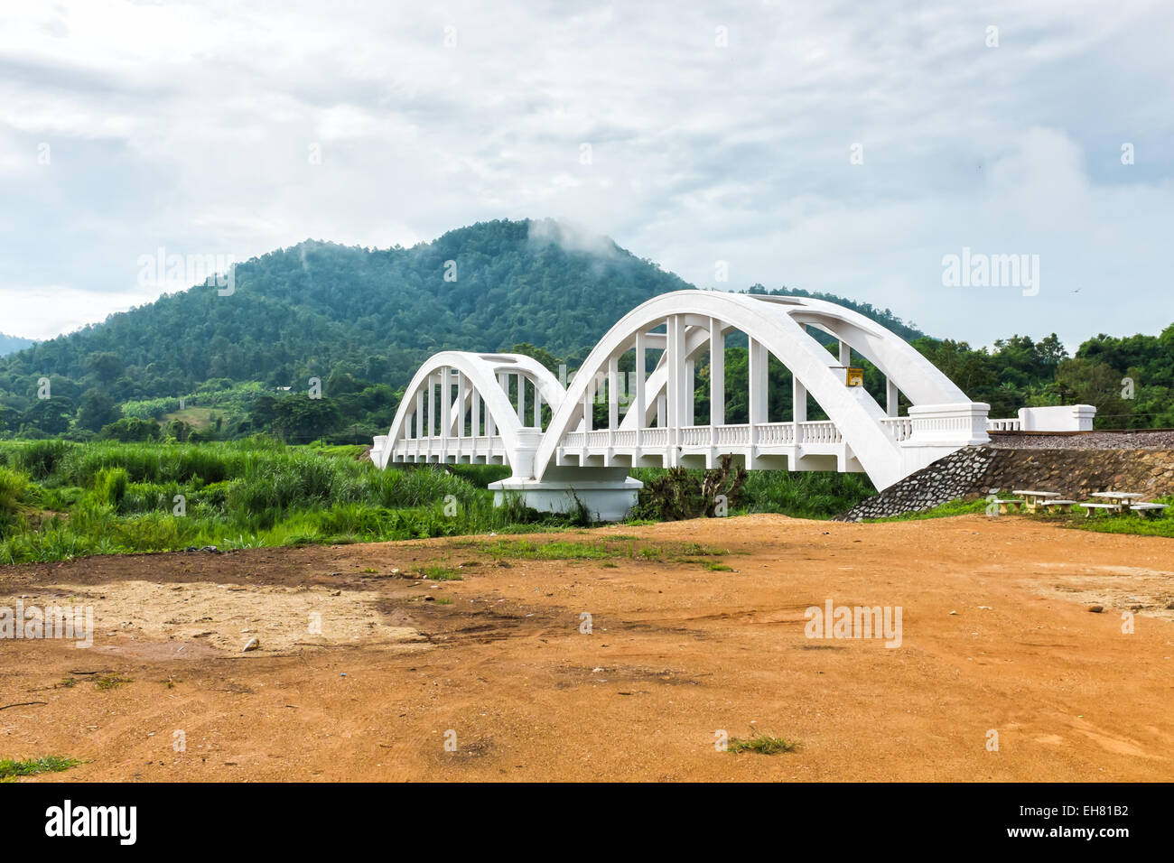 alte weiße Eisenbahnbrücke und die Berge im Hintergrund mit bewölktem Himmel Lamphun thailand Stockfoto