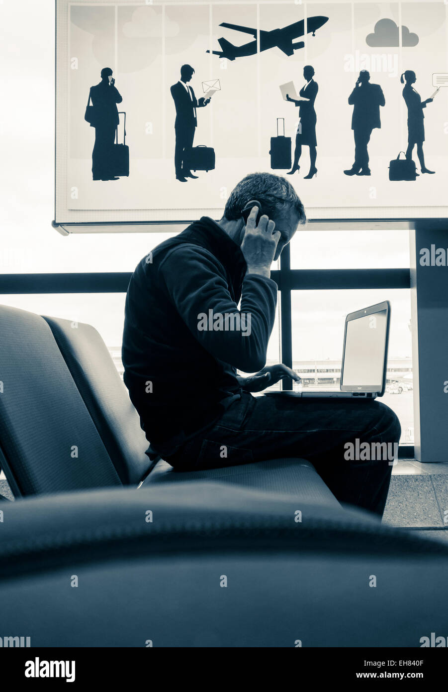Mann mit Laptop telefonieren mit Handy in Flughafen Wifi-Zone. UK Stockfoto