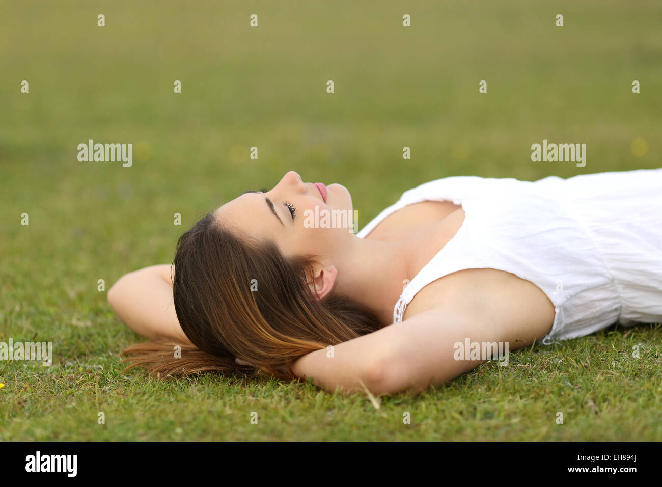 Entspannte Frau liegt auf dem Rasen schlafen in eine ruhige Szene mit einem grünen Hintergrund Stockfoto