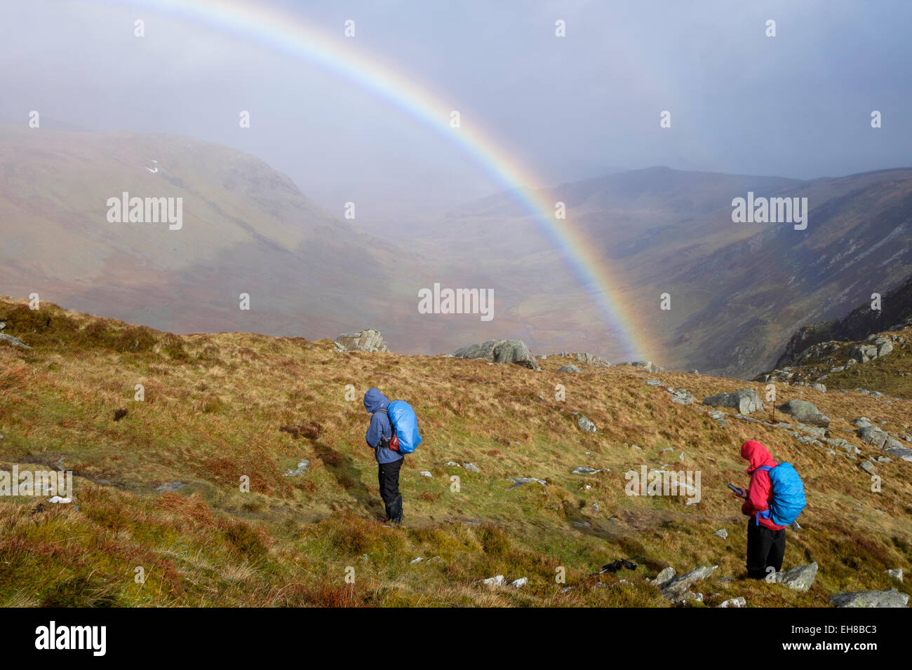 Wanderer Wandern bei nassem Wetter mit einem Regenbogen auf Stift yr Helgi Du in Carneddau Berge von Snowdonia National Park North Wales UK Stockfoto