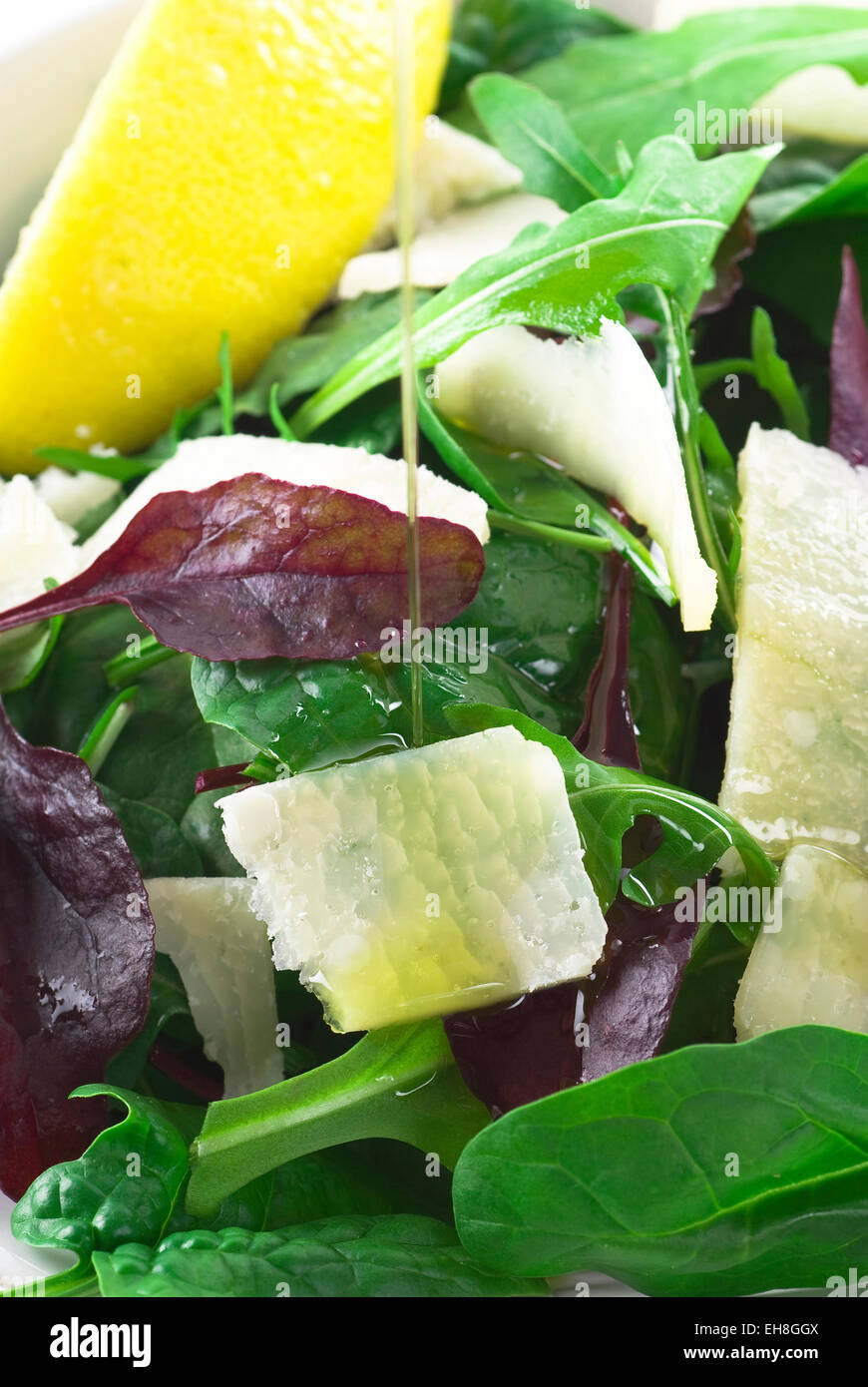 Gießen Olivenöl auf Salat mit Parmesan. Stockfoto
