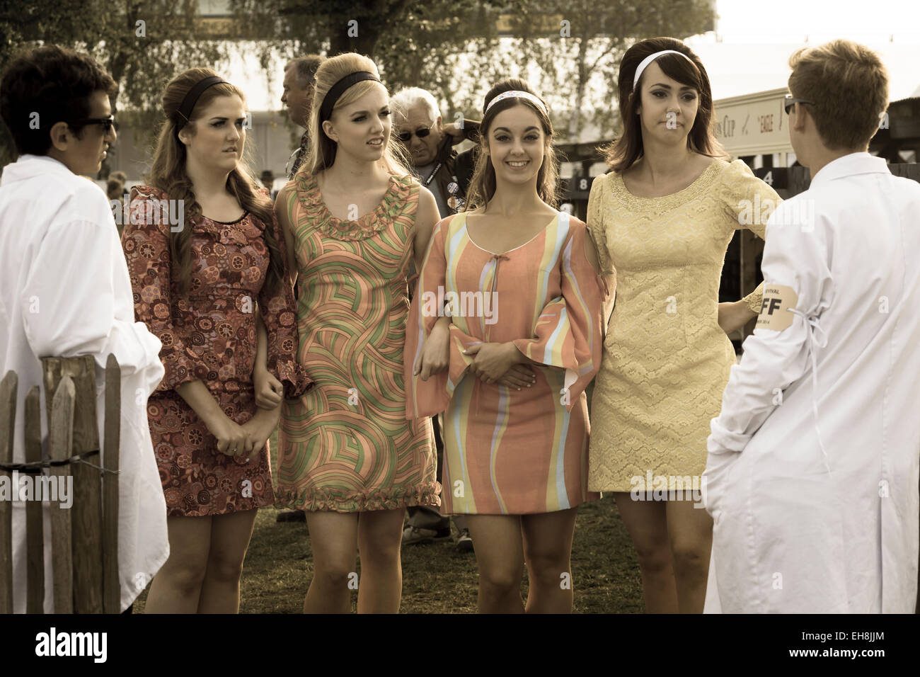 4 junge Frauen im Chat mit Verwalter in 60er Jahre Kleidung. 2014 Goodwood Revival Meeting, Sussex, UK. Stockfoto