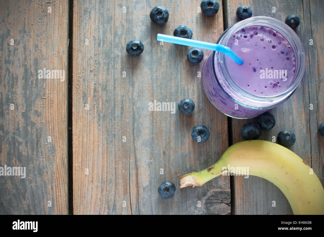 Heidelbeer-Smoothie mit Banane und Früchten auf einem hölzernen Hintergrund Stockfoto