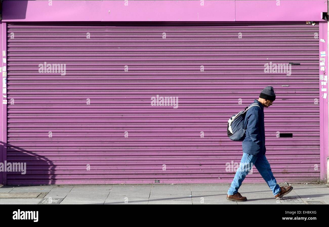 Einziger Mann zu Fuß vor dunkelrosa Schalung Southall Stockfoto