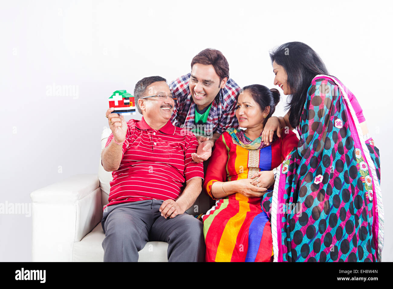 4 indische Erwachsene Eltern Sohn und Schwiegertochter sitzen Sofa Dummy-Haus anzeigen Stockfoto