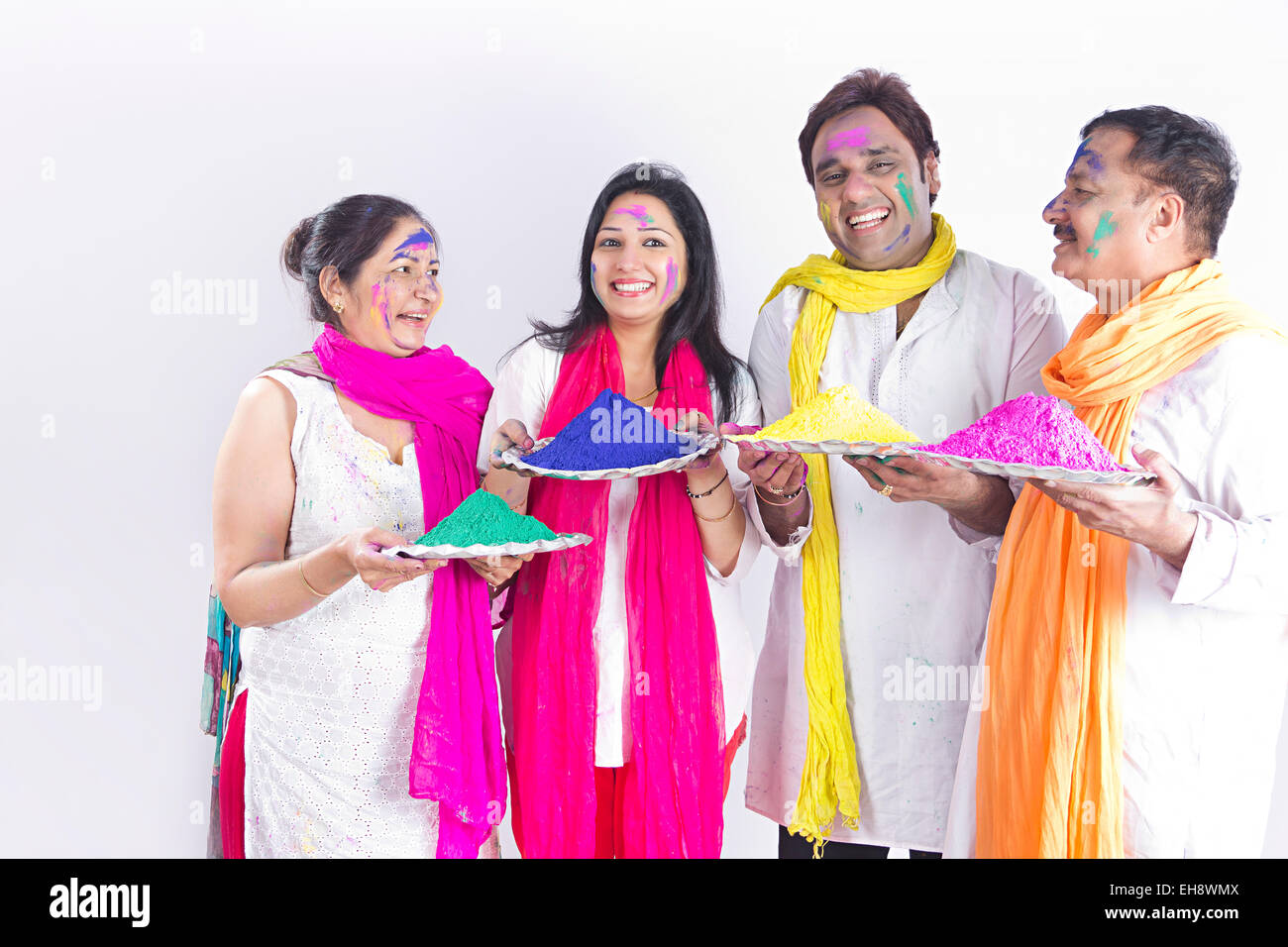 4 indische Erwachsene Eltern Sohn und Schwiegertochter Holi Festival Platte Farbe Holding willkommen Stockfoto