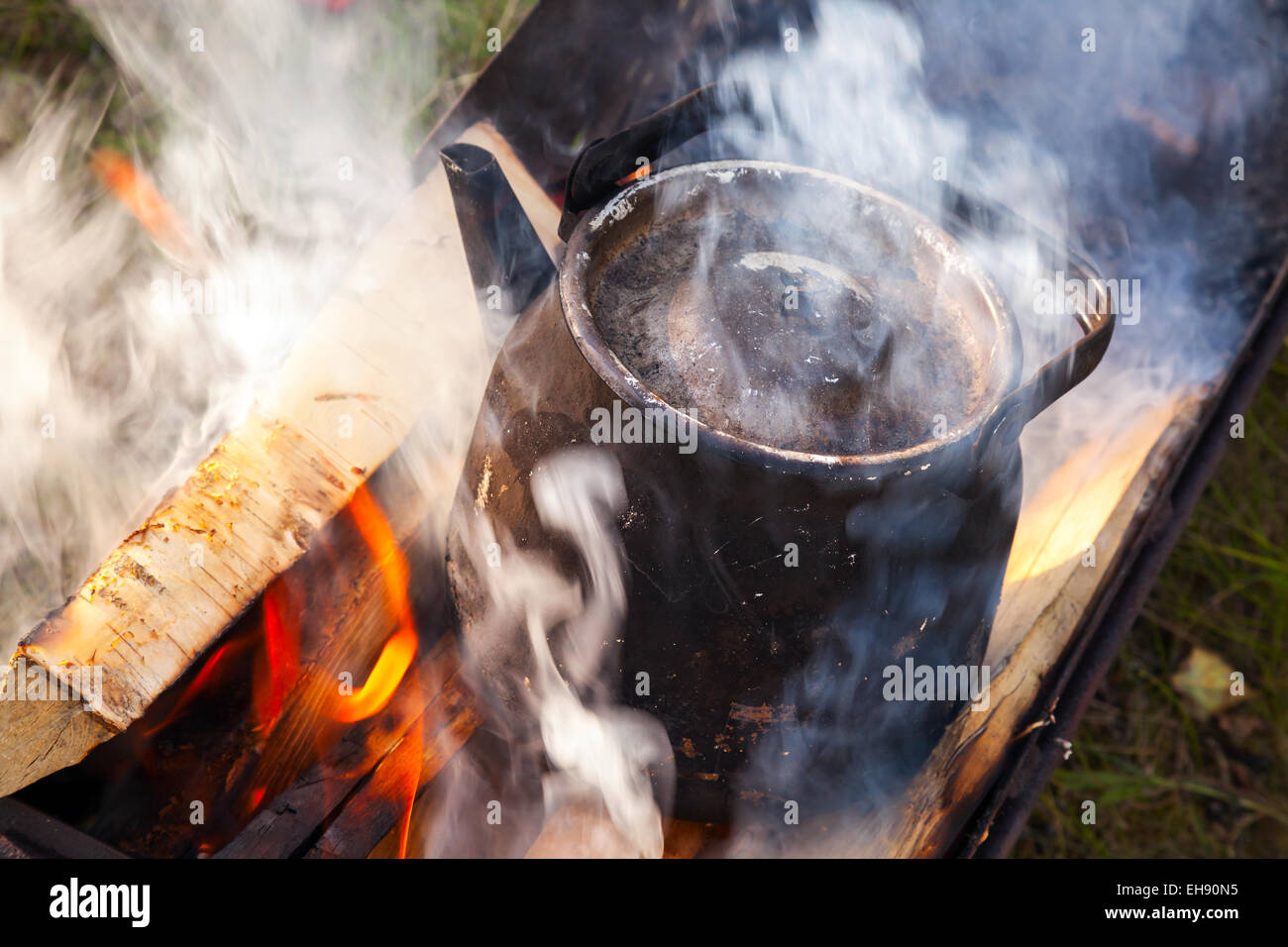 Lagerfeuer mit Rauch über Metall alte schwarze kochenden Teekanne Stockfoto