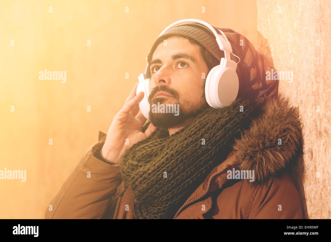 ein junger Mann hört Musik in einem städtischen Bild des modernen Lebens, warmen Tönen Stil getönt Stockfoto