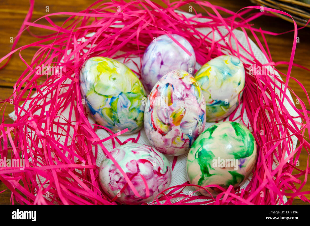 Bunt und bemalten Eiern in einem rosa Nest auf einem Holztisch Stockfoto