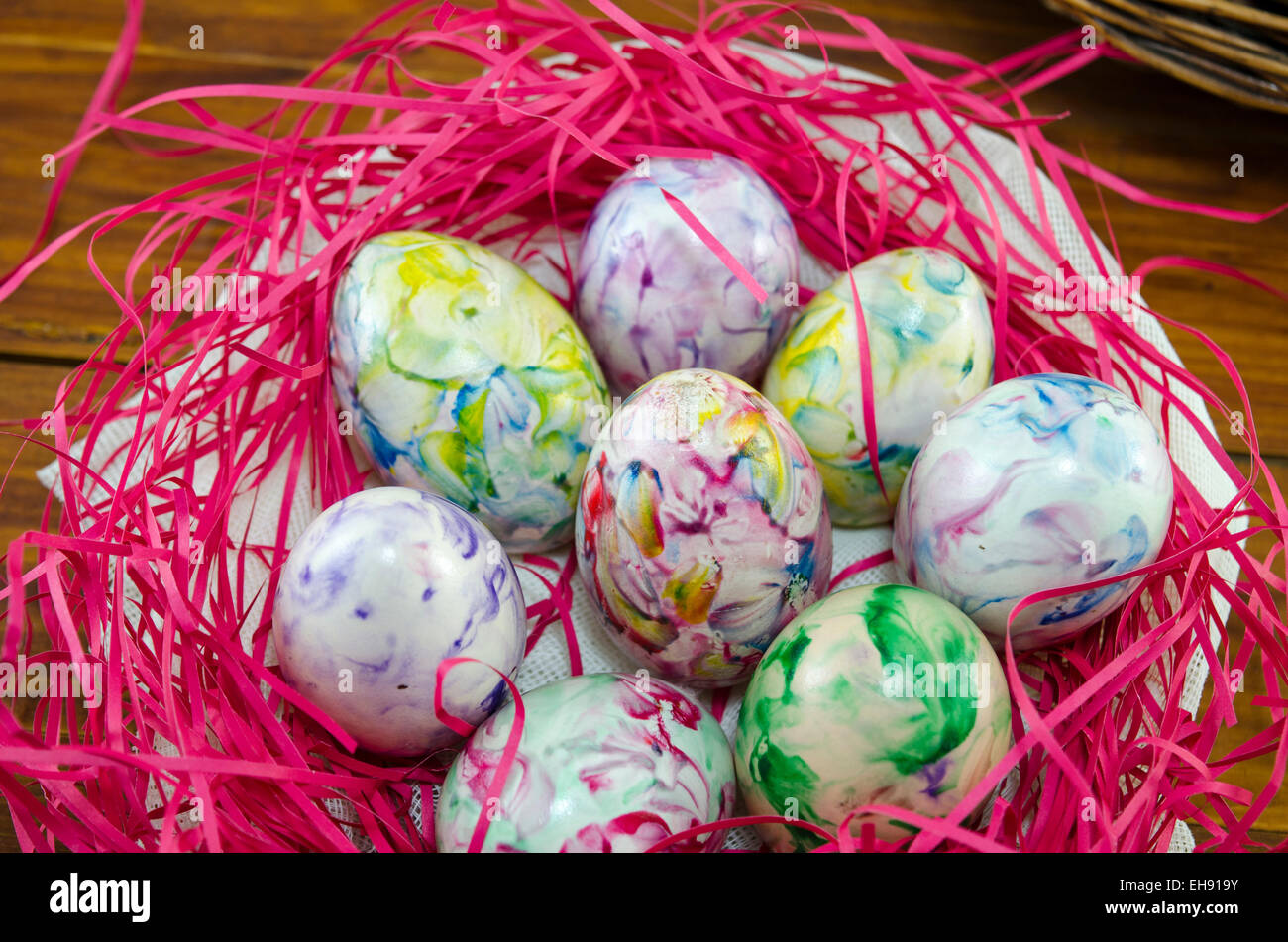 Bunt und bemalten Eiern in einem rosa Nest auf einem Holztisch Stockfoto