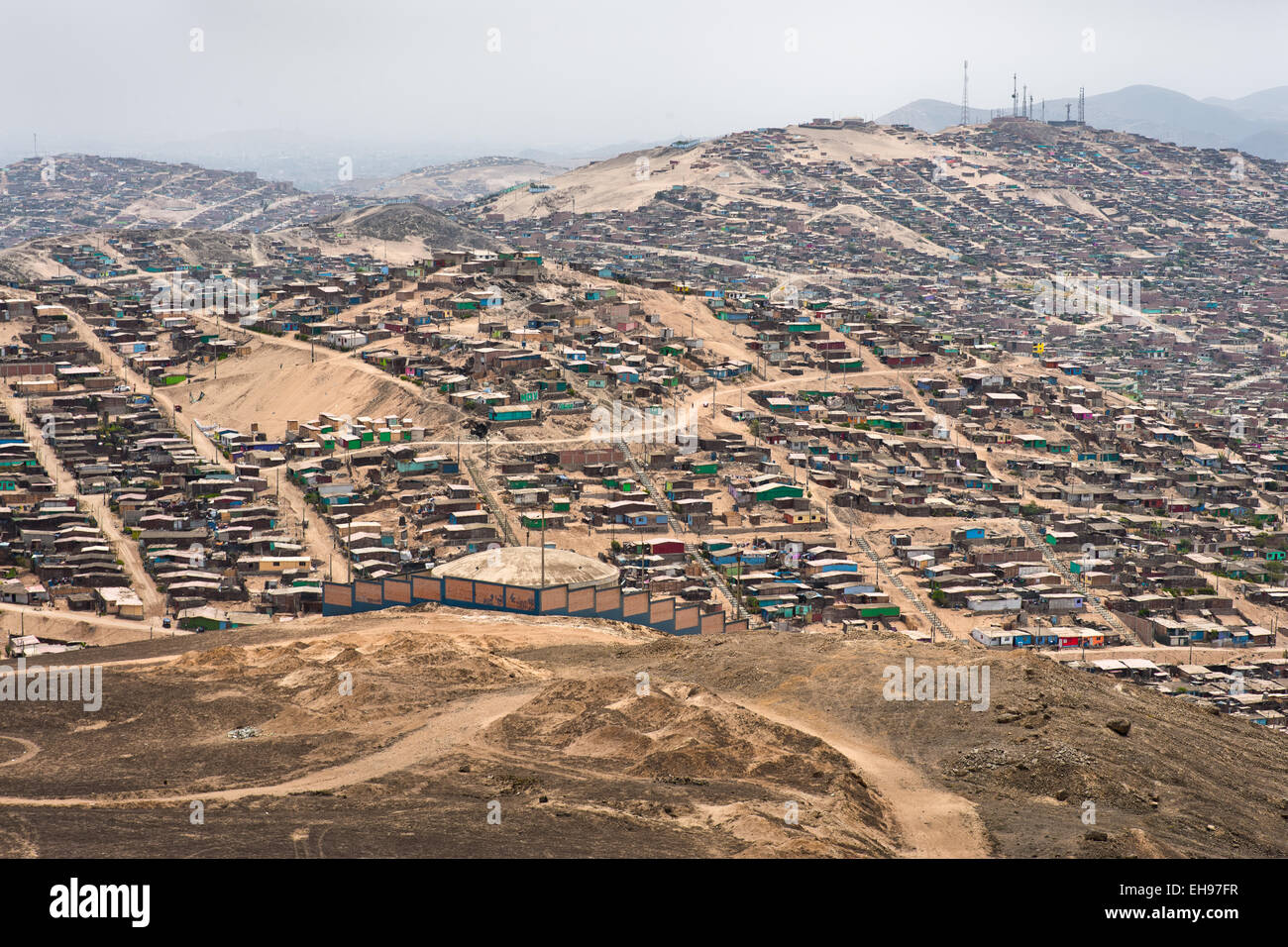 Eine weitläufige Siedlung von Häusern und Hütten aus Holz sieht man auf den staubigen Hügeln von Pachacútec, einem einsamen Vorort von Lima, Peru. Stockfoto