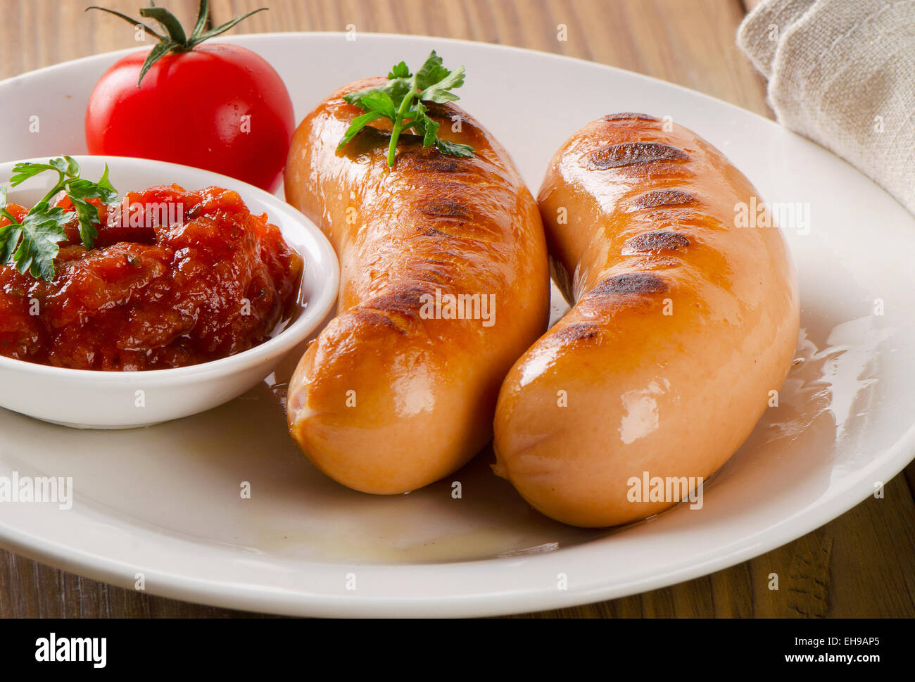 Gebratene Würstchen mit Tomatensauce und Kräutern. Selektiven Fokus Stockfoto