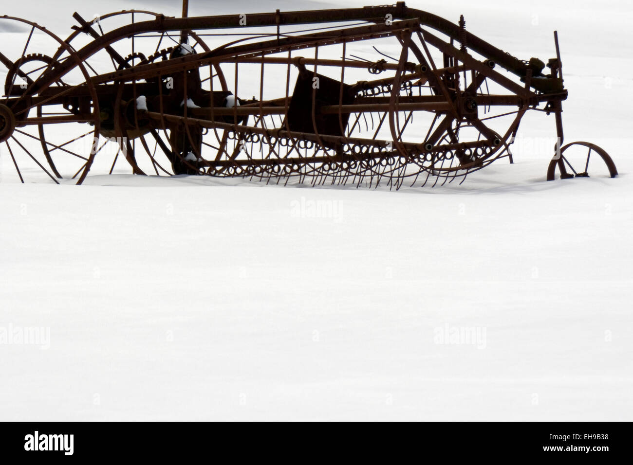 Ein antikes Stück von Landmaschinen sitzt im Schnee verworfen. Stockfoto