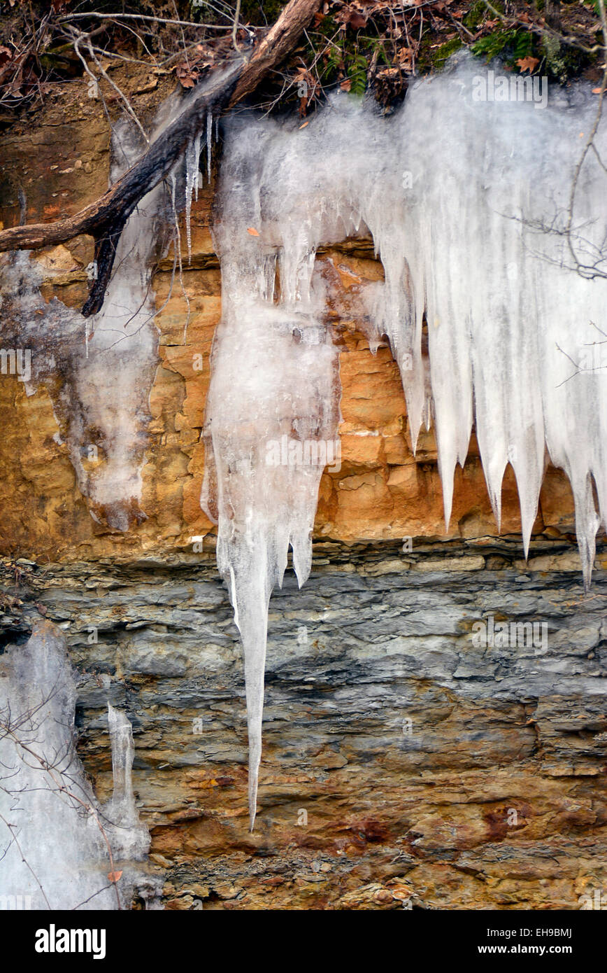 Eiszapfen nach unten fließen über freiliegende Schichten von Erde und Stein. Stockfoto