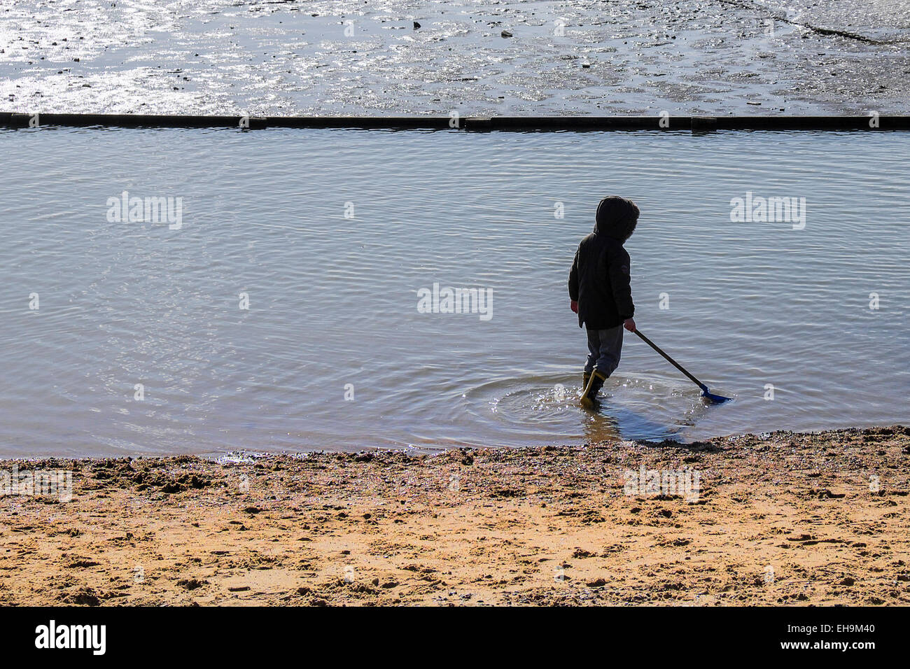Ein junges Kind allein spielen in der Gezeiten Planschbecken bei Leigh Bell Wharf Strand in Leigh-on-Sea, Essex. Stockfoto