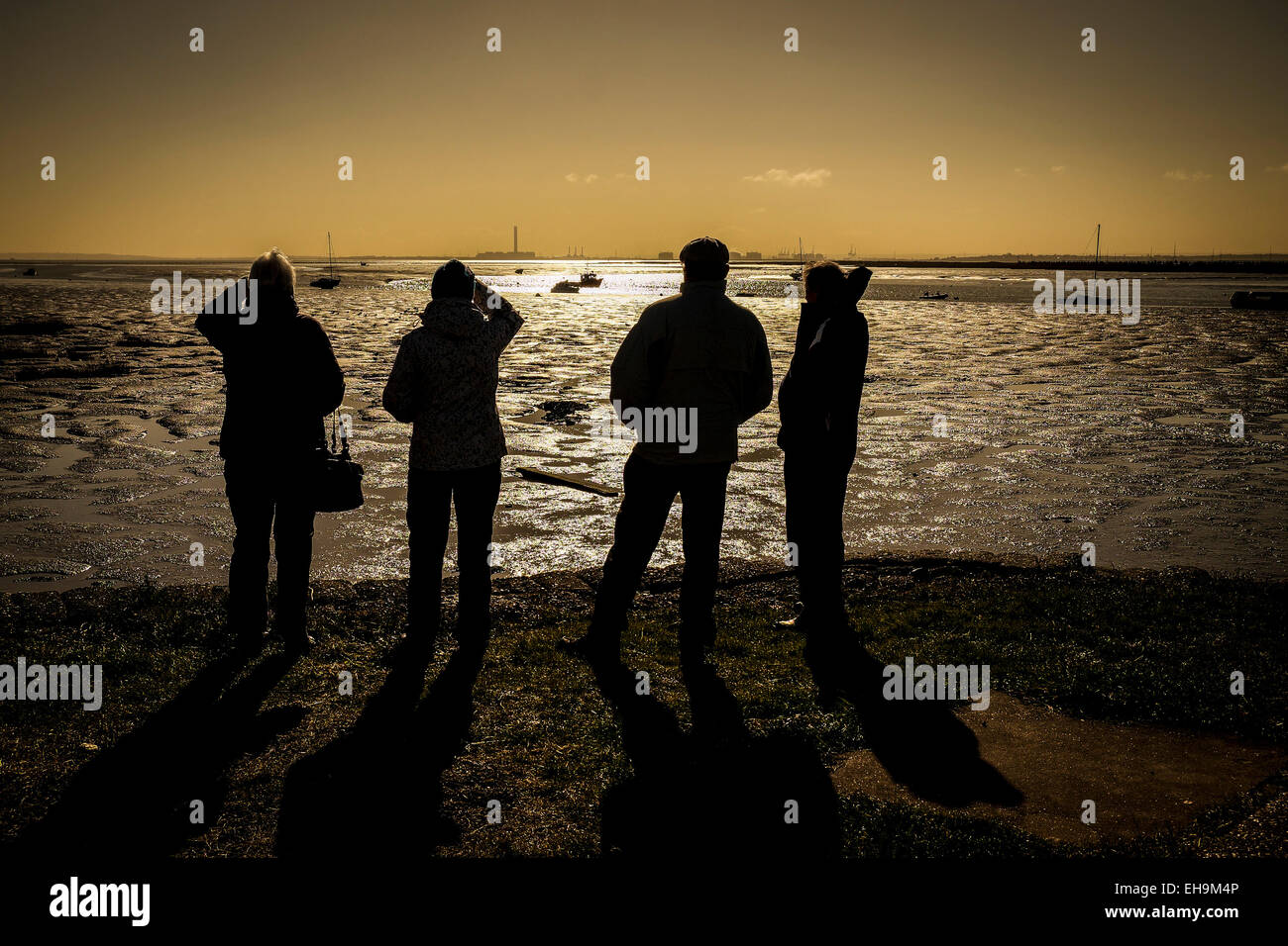 Die Silhouette einer Gruppe von Personen, die über die Mündung der Themse suchen bei Sonnenuntergang in Essex. Stockfoto
