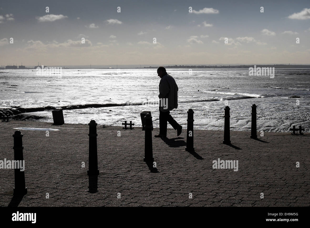 Die Silhouette eines Mannes zu Fuß bei Bell Wharf bei Ebbe in Leigh-on-Sea, Essex. Stockfoto