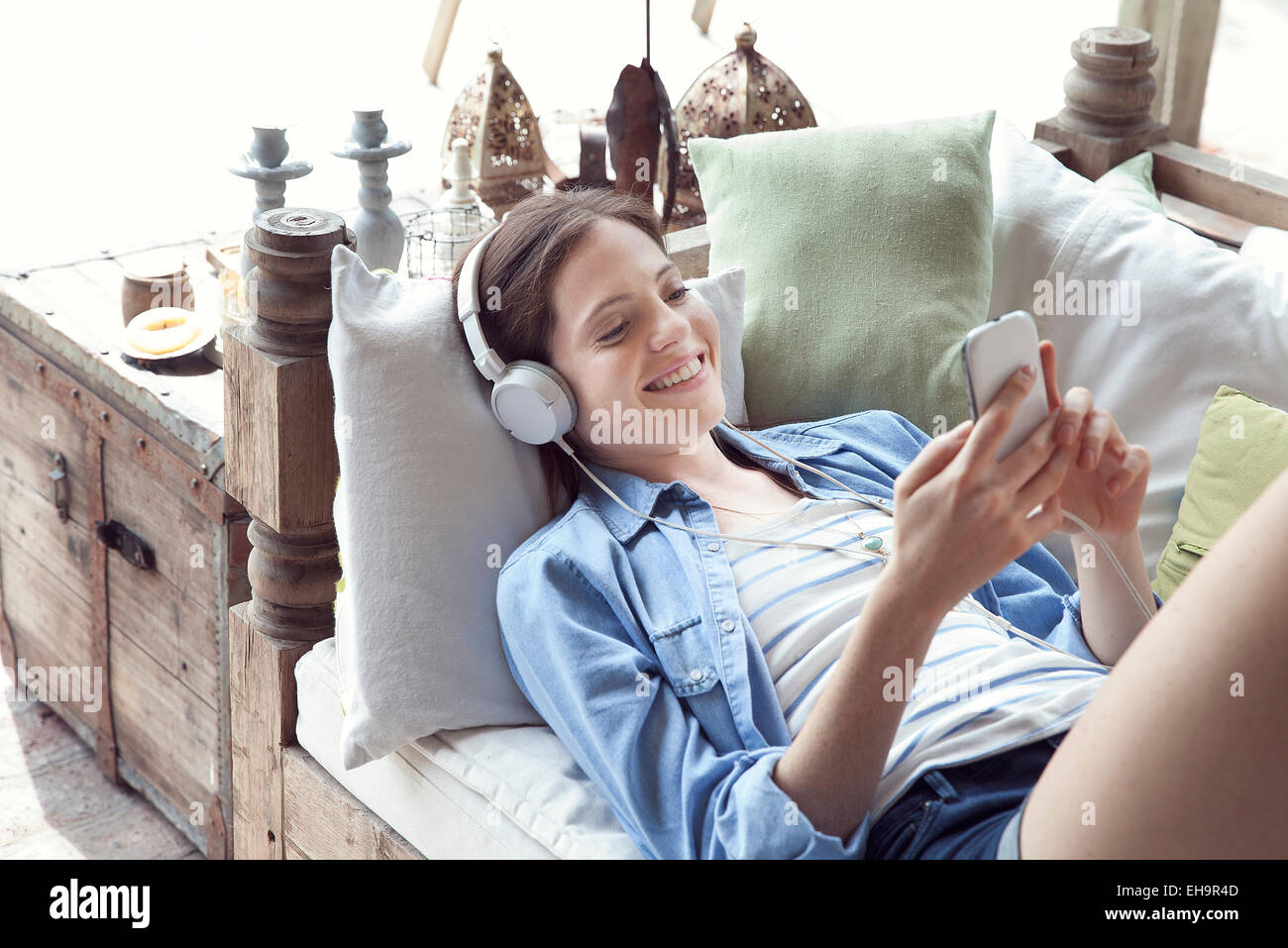 Junge Frau entspannend mit Smartphone und Kopfhörer Stockfoto