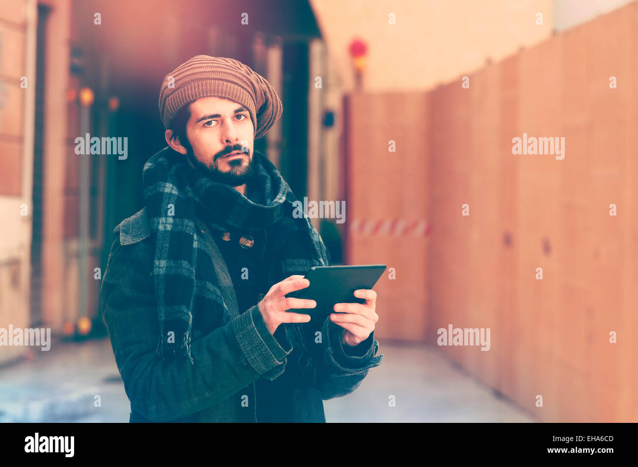junger Mann hält eine Tablette in städtischen im Freieneinstellung Warmton-Filter angewendet Stockfoto