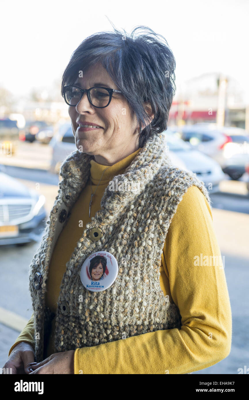 Merrick, New York, USA. 9. März 2015. RITA KESTENBAUM, 56, Bellmore, Kandidat der Demokraten für das Nassau County Gesetzgeber 19. Bezirk, trägt eine Schaltfläche "Kampagne", wie sie am Bahnhof Merrick am Vorabend des Wahltages Kampagnen. Kestenbaum, Gewehrsteuerung Aktivist und republikanischen S. Rhoads, 46, der Bellmore, stehen einander in eine Nachwahl statt, um die freie Stelle als ehemalige Gesetzgeber D. Denenberg (D-Merrick) trat zurück, nachdem er schuldiges zu Kapitalverbrechen Mail-betrug plädierte zu füllen. Die Kestenbaum Tochter Carol und ein Freund wurden in 2007 ermordet. (Kredit-Bild: © Ann Parry/ZUMA Wi Stockfoto