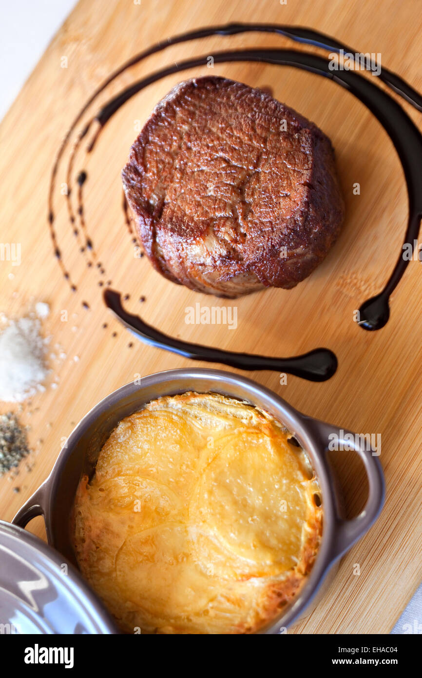 Rind Steak und Kartoffeln Gratin auf einem Holzbrett Stockfoto
