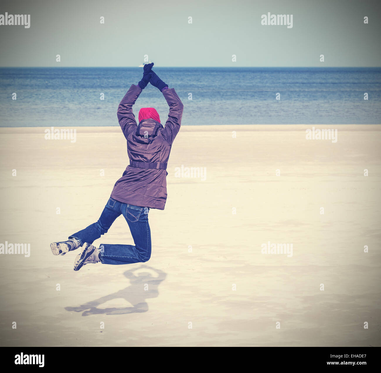 Retro-gefilterte Foto Frau am Strand, Winter aktiven Lifestyle-Konzept, Raum für Text springen. Stockfoto