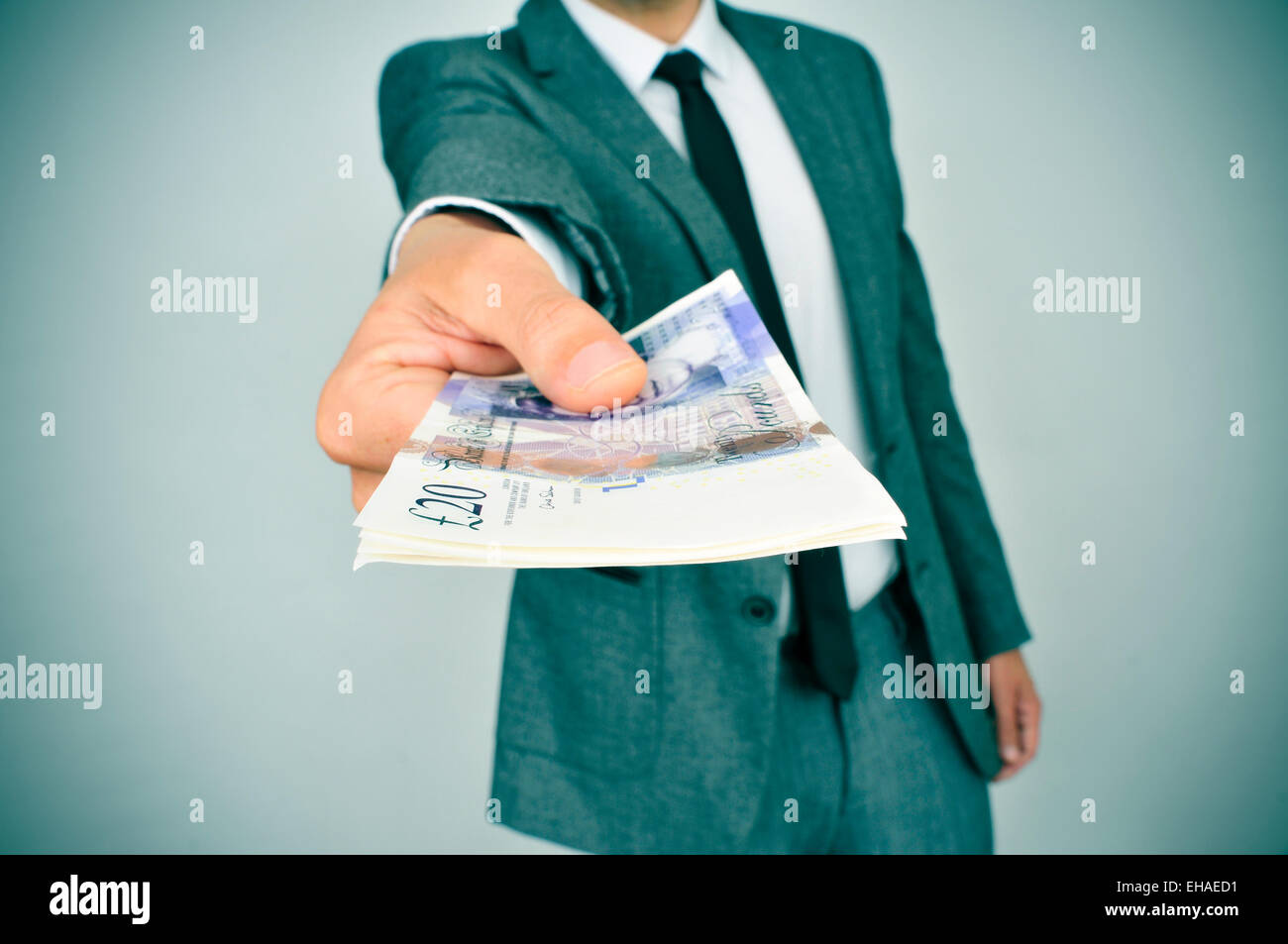 ein junger Mann im Anzug verleiht des Beobachters ein Bündel von Pfund Sterling Rechnungen Stockfoto