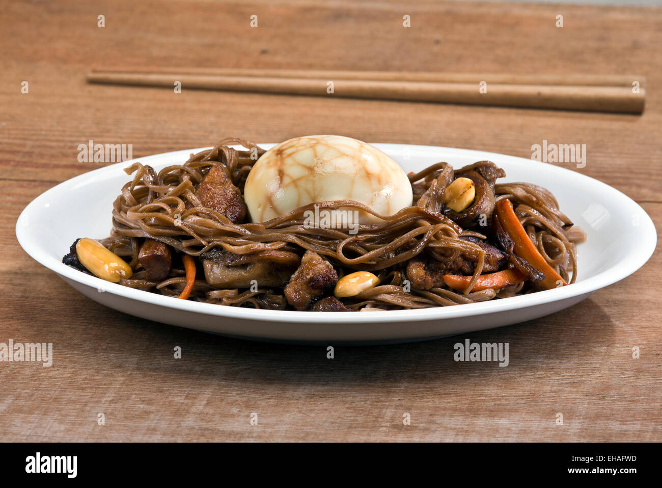 Traditionelle chinesische Tee-Ei auf ein Nest von gebratenes Soba-Nudeln mit Schweinefleisch, Austernpilze und Erdnüssen serviert. Stockfoto