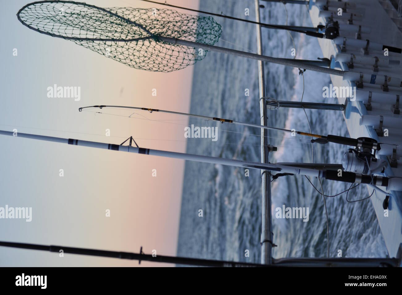 Angeln, Boot Edge mit Stangen und Netz mit Sonnenuntergang Hintergrund Stockfoto