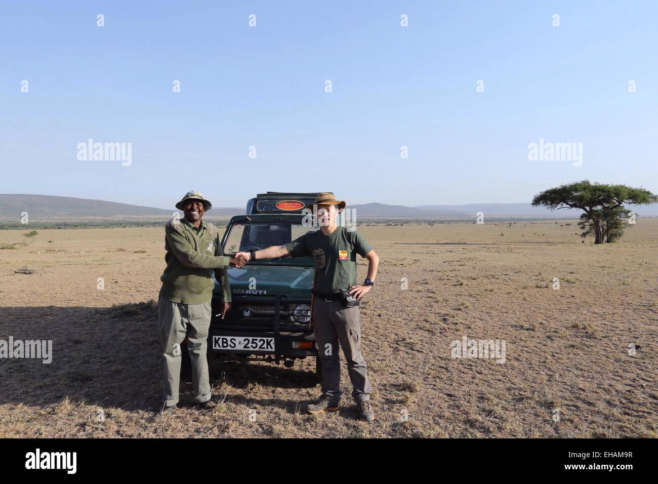 Masai Mara, Kenia. 10. März 2015. Zhuo Qiang (R), Gründer von Mara Conservation Fund, schüttelt Hände mit Simon Nkoitoi, senior-Chefin mit OL Kinyei Conservancy in der Masai Mara, Kenia, am 10. März 2015. Mara Conservation Fund, ein Chinesisch-geführten Organisation gespendet Dienstag ein Fahrzeug an der OL Kinyei Conservancy, der Rangers Kampf gegen Wilderei, ebenso wie die Bewegungen der Raubkatzen wie Löwen studieren zu helfen. © Pan Siwei/Xinhua/Alamy Live-Nachrichten Stockfoto