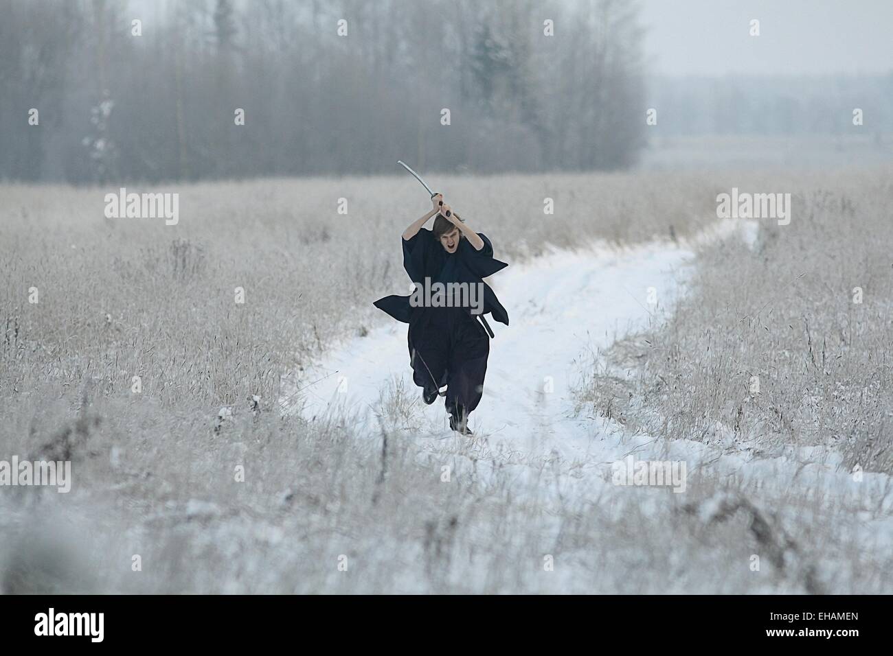 Samurai trägt einen Kimono in einem Winter Feld laufen gekleidet in schwarz, frost Stockfoto