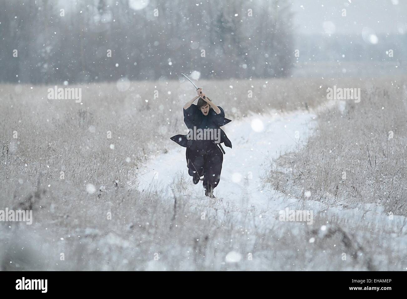 Samurai trägt einen Kimono in einem Winter Feld laufen gekleidet in schwarz, frost Stockfoto