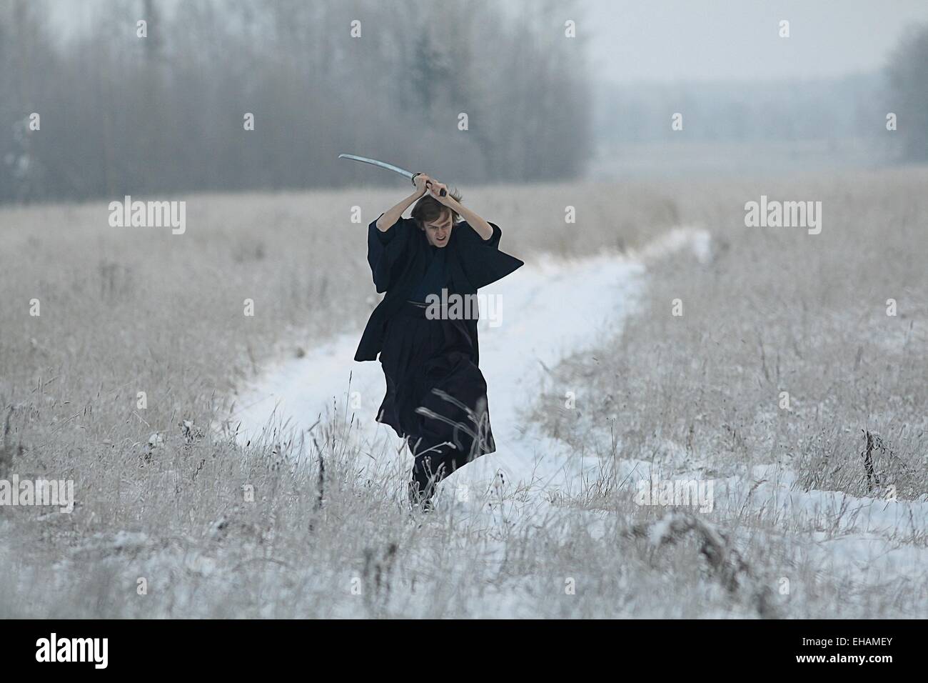 Samurai trägt einen Kimono in einem Winter Feld laufen gekleidet in schwarz, frost Stockfoto