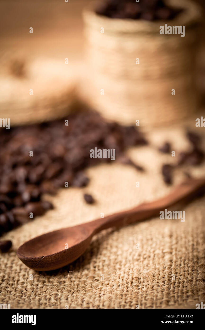 Haufen von Kaffeebohnen und Holzlöffel mit Platz für Text, Fokus auf Löffel mit flacher Fokus Stockfoto