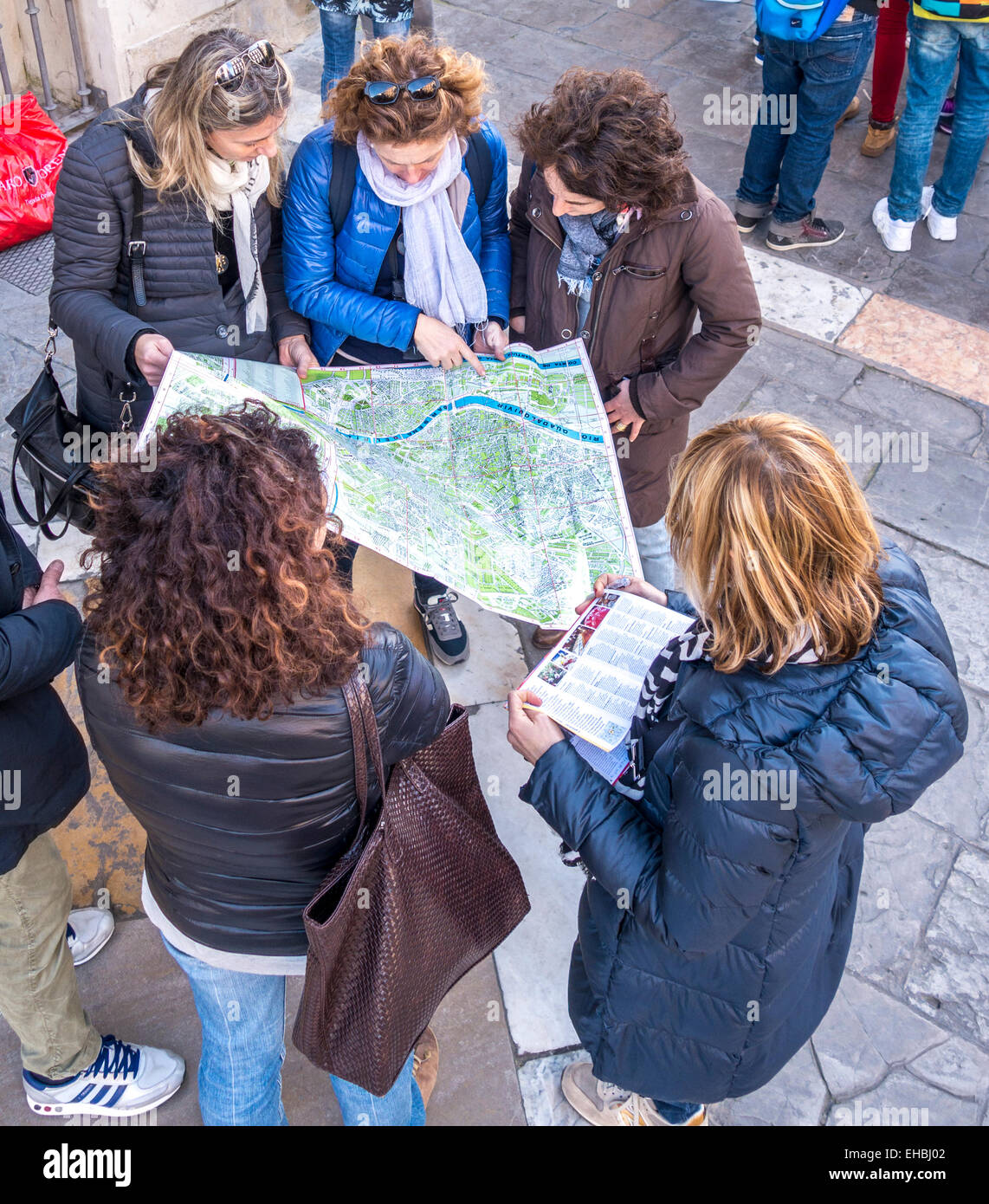 Gruppe von fünf Mädchen, junge Frauen, Touristen auf der Suche auf eine touristische Karte von Sevilla Spanien zeigen und diskutieren Richtungen Stockfoto