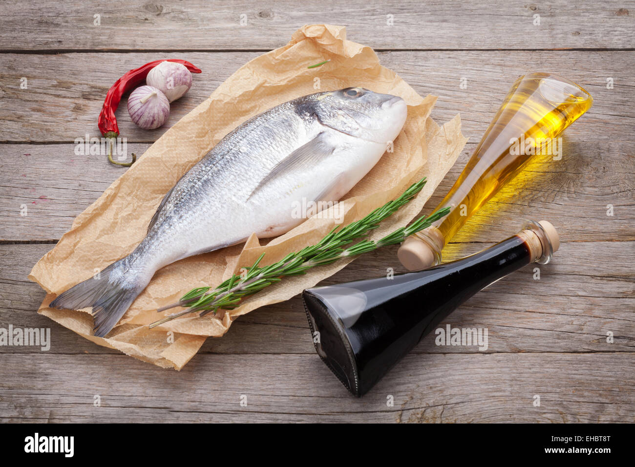 Dorado Frischfisch Kochen mit Gewürzen und Zutaten auf Holztisch Stockfoto