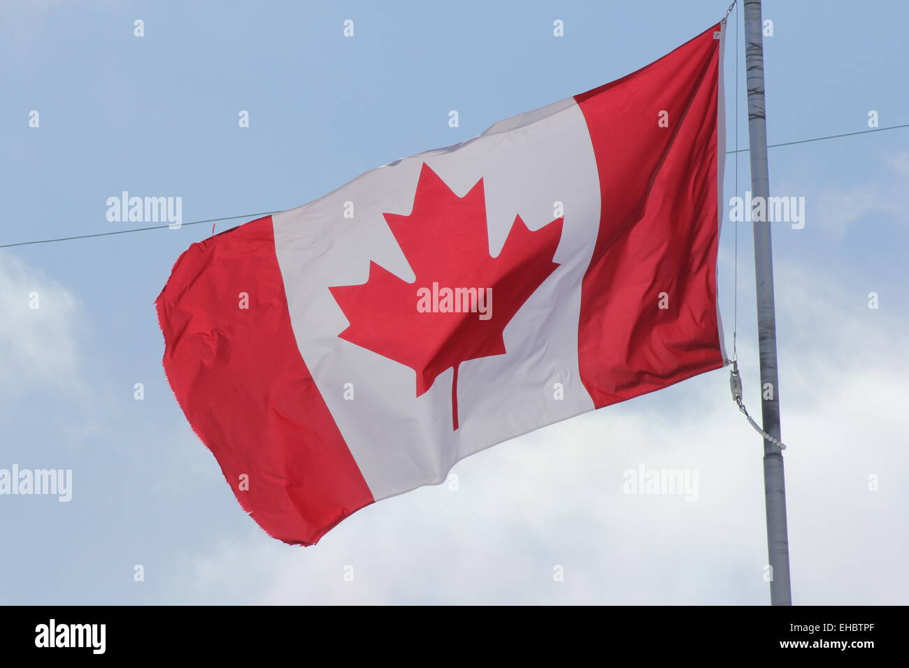 Kanadische Flagge winken sanft in einer leichten Brise gegen Wolken und blauer Himmel. Stockfoto