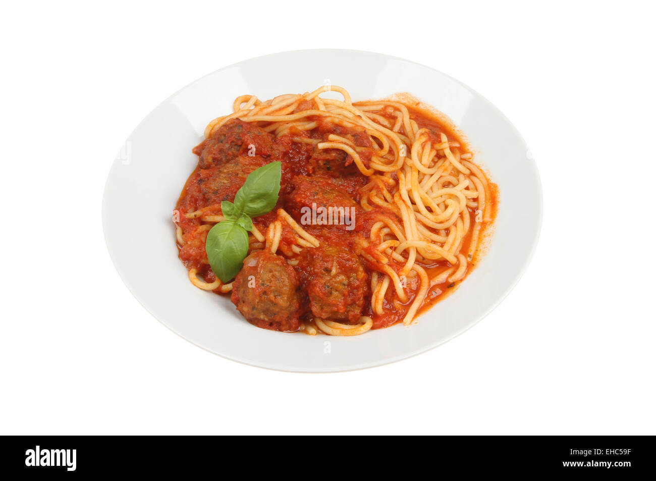 Spaghetti und Fleischbällchen mit einem Zweig Basilikum in eine Schüssel geben, isoliert gegen weiß Stockfoto