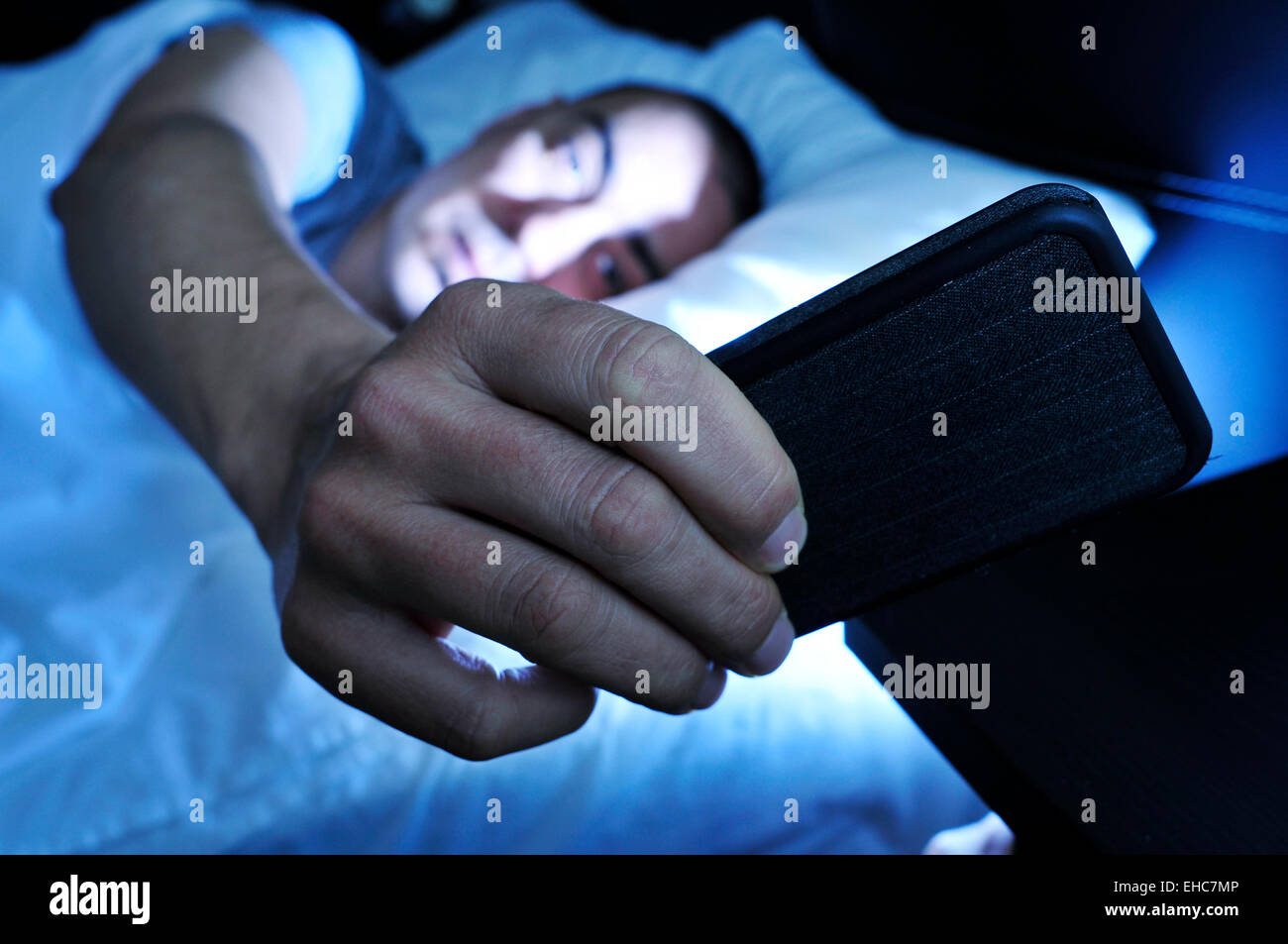 Nahaufnahme eines jungen Mannes im Bett, Blick auf das Smartphone in der Nacht Stockfoto