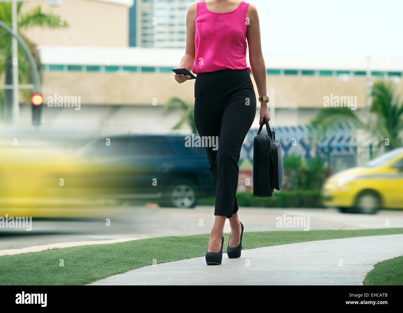 Blick auf Business-Frau zu Fuß in die Stadt Straße mit Laptop-Tasche, im Chat auf Handy und gehen morgens zur Arbeit beschnitten Stockfoto