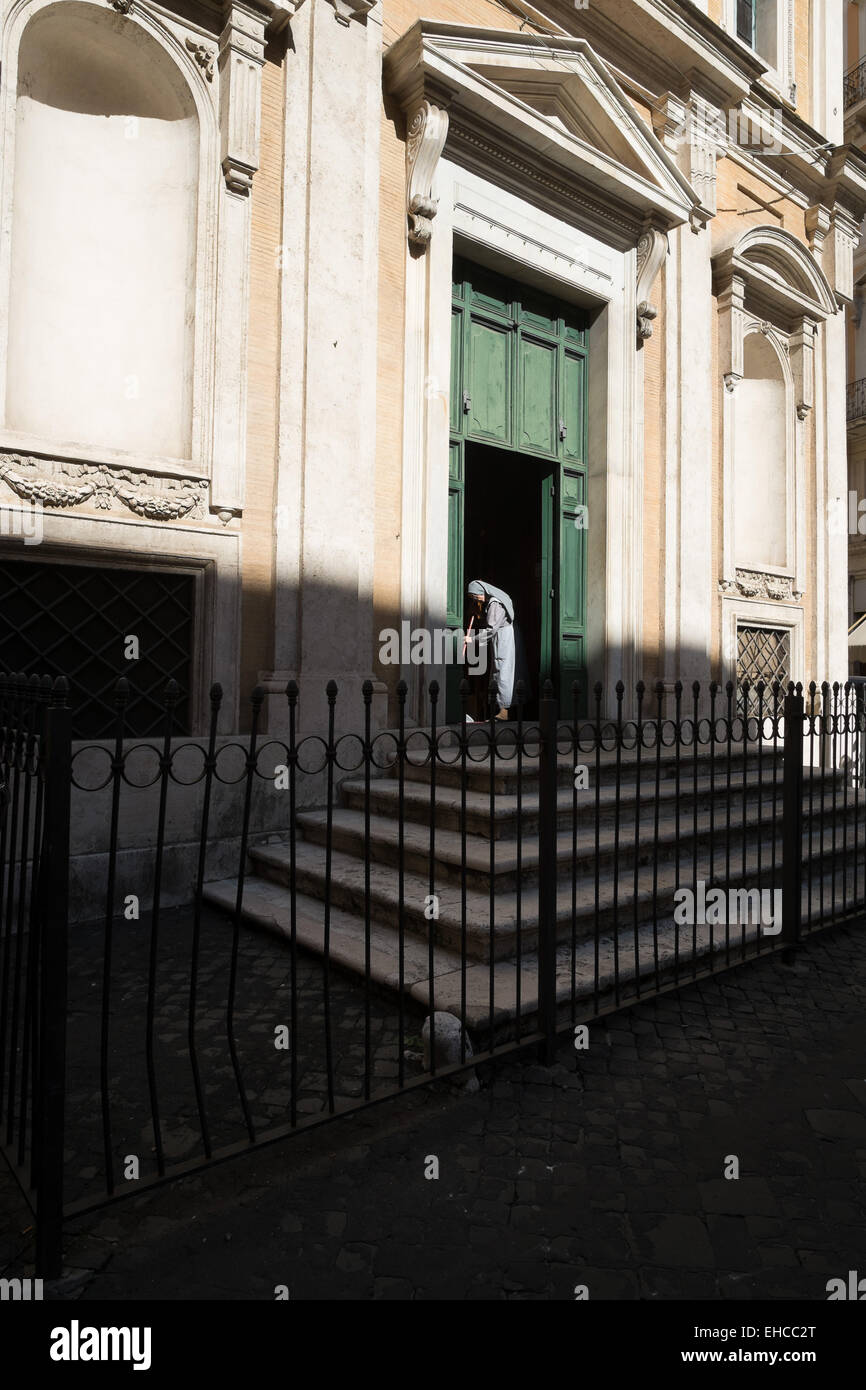 Roman Nun fegt den Boden einer alten Kirche Eingang in der Innenstadt von Rom. Stockfoto