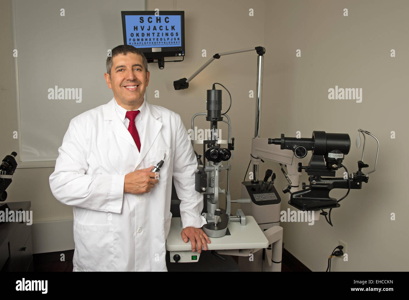 Hispanische Augenarzt im Untersuchungsraum umgeben von Prüfmaschinen Stockfoto