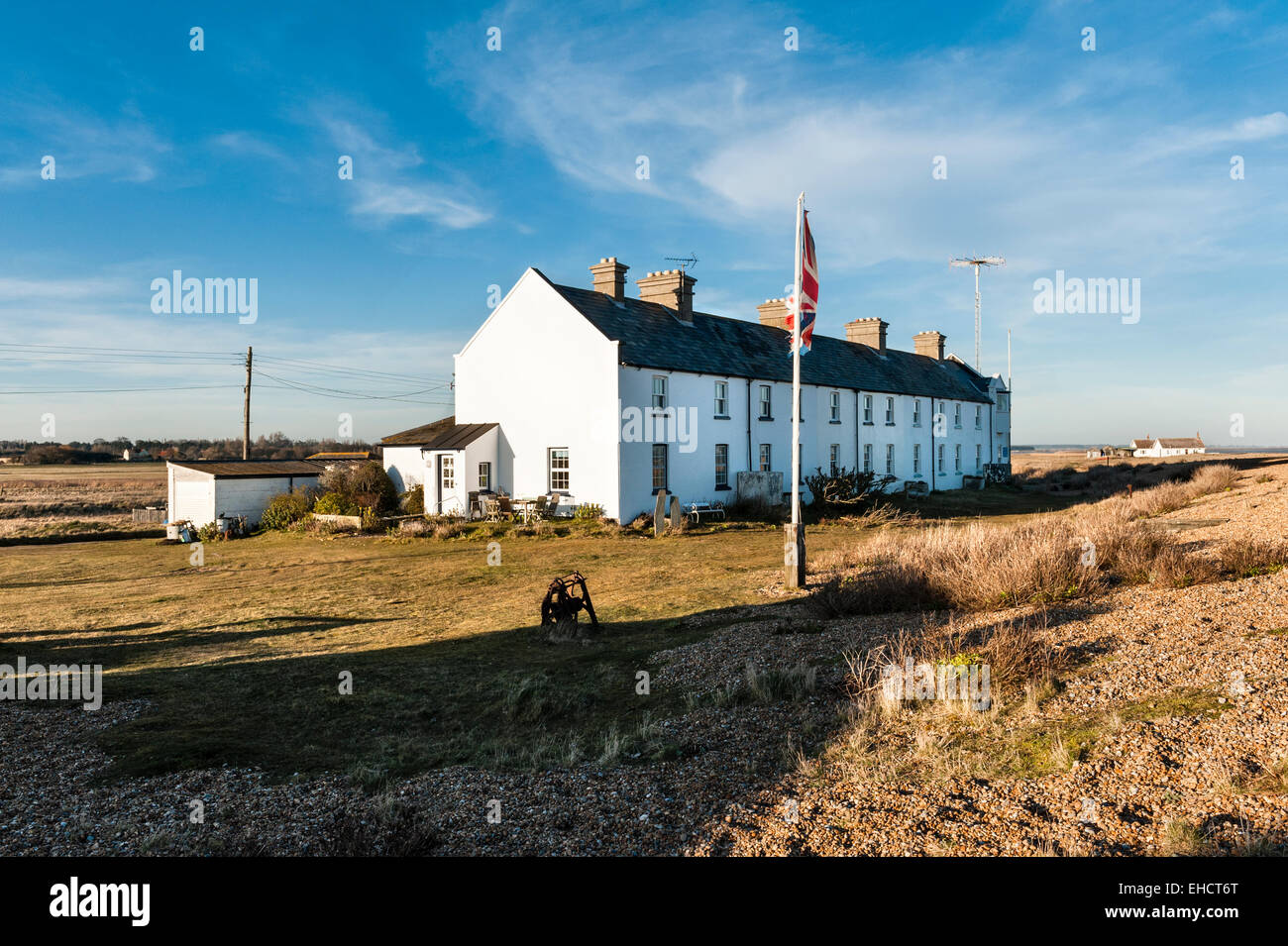 Eine Reihe alter Cottages der Küstenwache im abgelegenen Dorf Shingle Street, Suffolk, an der britischen Ostküste. Ein Kommunikationsturm befindet sich auf der rechten Seite Stockfoto