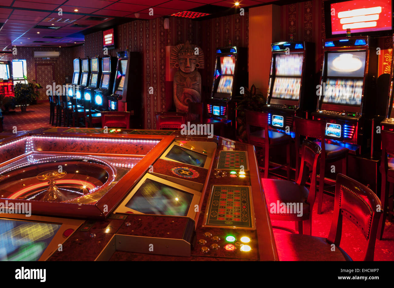Roulette-Tisch und Spielautomaten. Rot beleuchtete Casino. Stockfoto