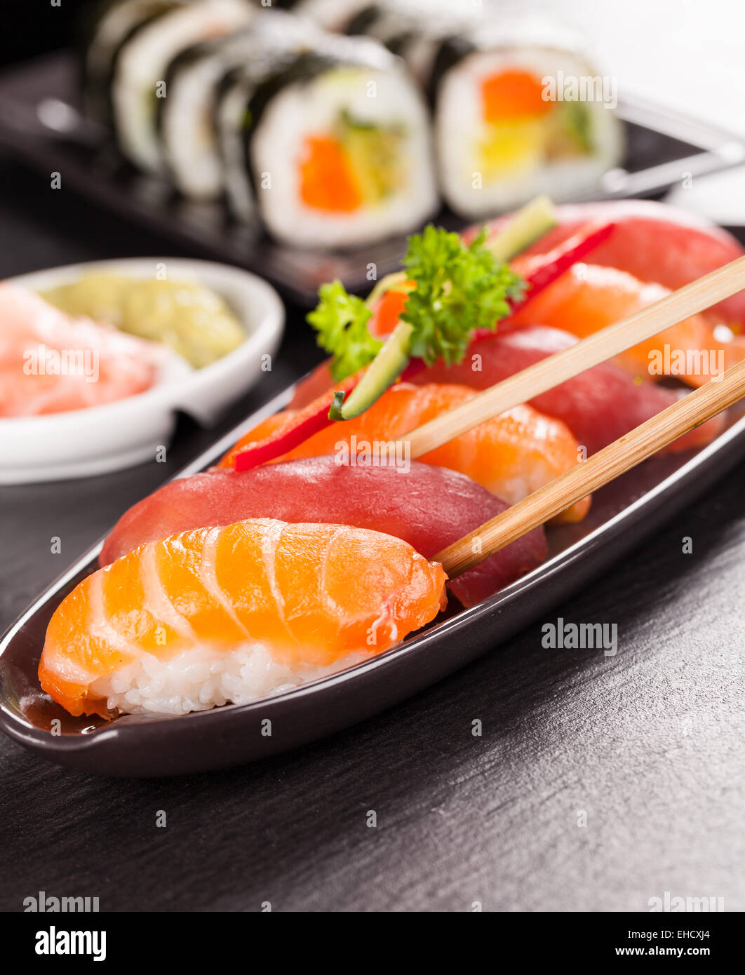 Leckere Sushi Lachs Brötchen serviert auf schwarzem Teller und Stein Stockfoto