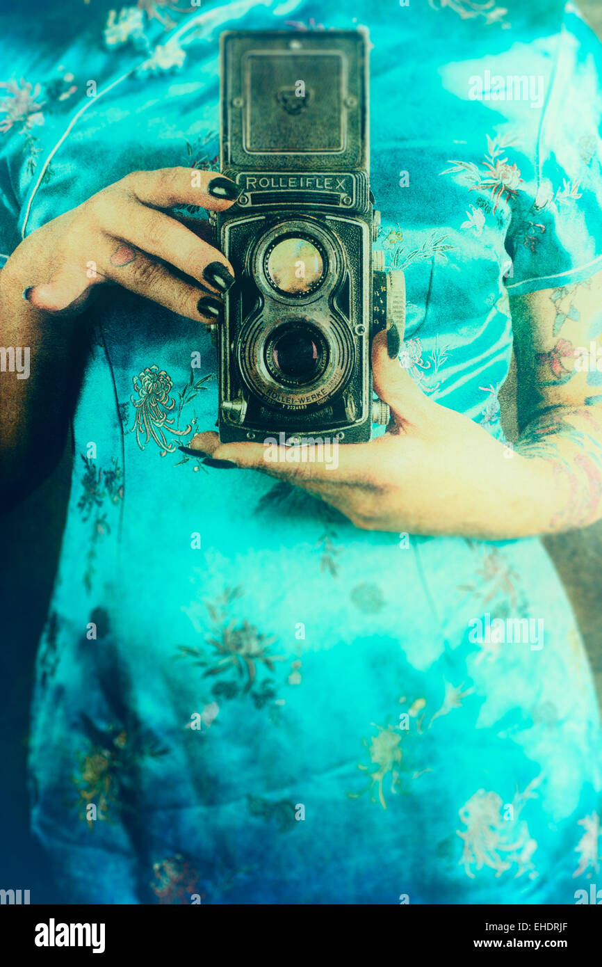 Frau trägt ein chinesisches Kleid eine Vintage Rolleiflex Kamera halten Stockfoto