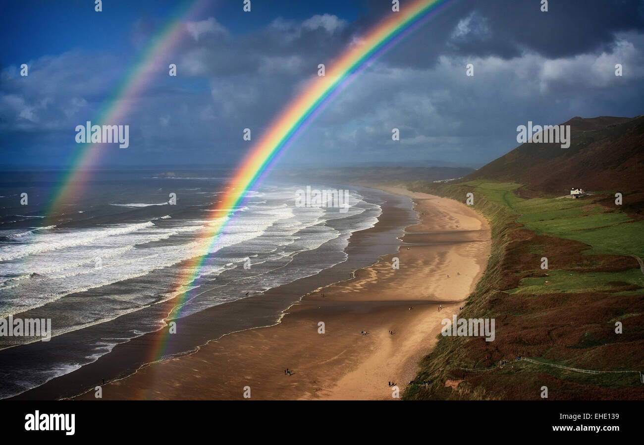 Rhossili Gower doppelter Regenbogen über Strand Surf weißes Haus in Ferne Bereich grün und Hügel mit Stockfoto