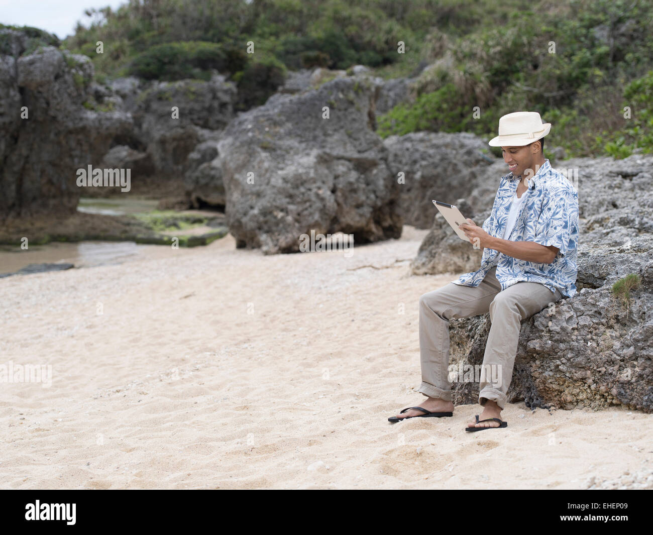 Mann am Strand mit einem iPad Stockfoto