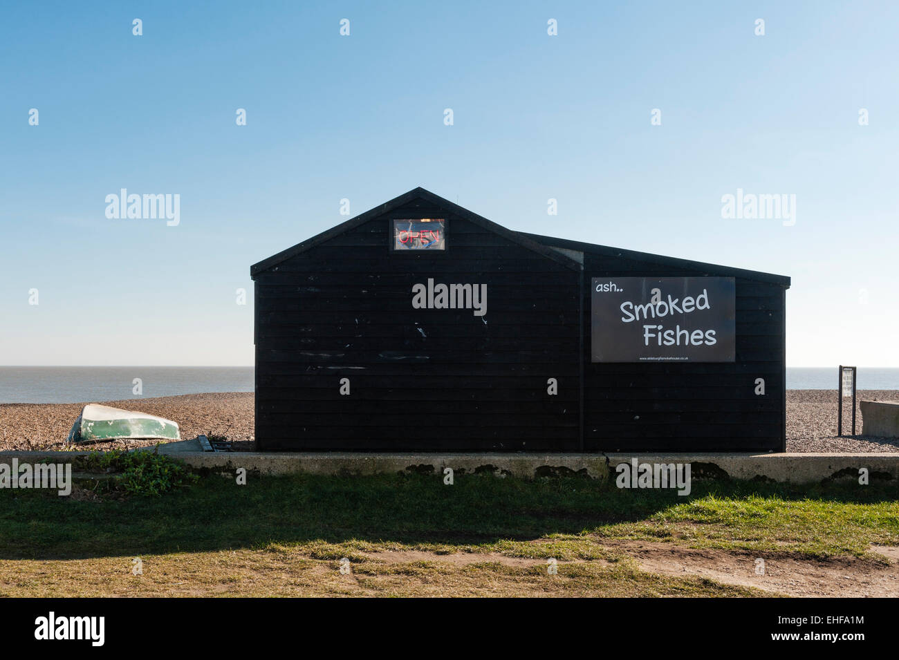 Aldeburgh, Suffolk, UK. Eine kleine schwarze Fisch-Rauchen-Hütte am Strand, mit einem "offenen" roten Neon-Schild Stockfoto